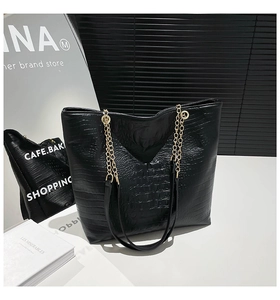 Close-up of black crocodile pattern tote bag with gold metal chain shoulder strap detail