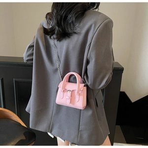 Rear view of a model wearing a pink mini crossbody bag with silver chain and buckle