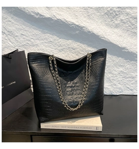 Detail of black crocodile texture tote bag featuring a premium gold metal chain strap