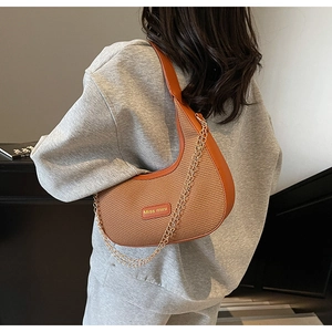 Detail showing woven texture and leather trim on a crescent shoulder bag with gold chain