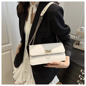 White leather shoulder bag with golden chain strap worn by a model in a black blazer