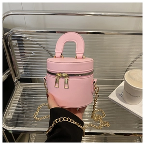 Detail der rosa zylindrischen Handtasche mit Doppelreißverschluss und goldener Kette im Lifestyle