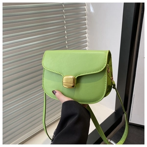 Detail of neon green saddle bag featuring a gold rectangular twist lock and slim strap