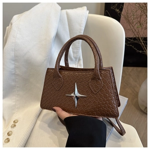 Detail of a brown woven square handbag with a silver star ornament and shoulder strap