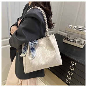 Detail of white woven texture tote bag with braided handle and floral scarf accent