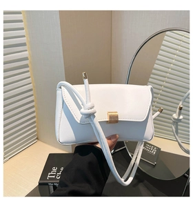 Detail of white leather shoulder bag with gold metal clasp and knotted strap detail