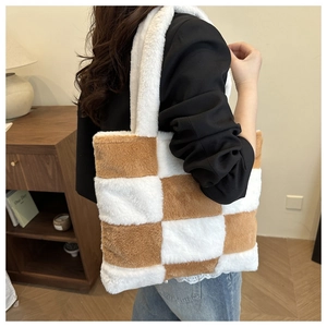 Detailed side view of the brown and white plush checkered tote bag worn by a model