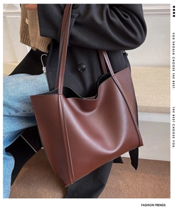 Detail of dark brown leather tote bag with fine stitching on a shoulder carry model