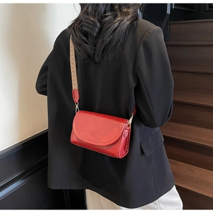 Red polished leather crossbody bag with wide jacquard strap shown on person