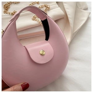 Detailed view of pink crescent bag with golden magnetic clasp and metallic chain strap