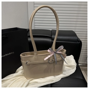 Détail du sac en cuir beige avec ruban décoratif et boucles métalliques élégantes