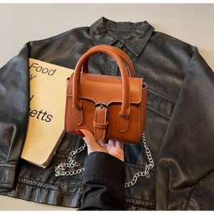 Détail du mini sac rétro en cuir orange-brun avec chaîne argentée et boucle décorative