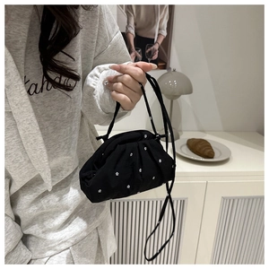 Détail d'un sac bandoulière plissé en mousseline noire avec motif floral blanc