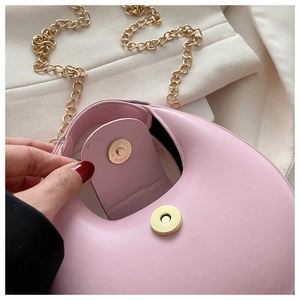 Detail of pink crescent bag showing magnetic snap closure and gold chain strap