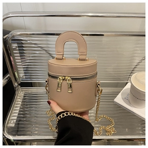 Detail der beigen zylindrischen Tasche mit goldenem Doppelreißverschluss und Kettenriemen