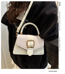 Close-up of white crossbody bag with woven texture flap and gold metal square buckle