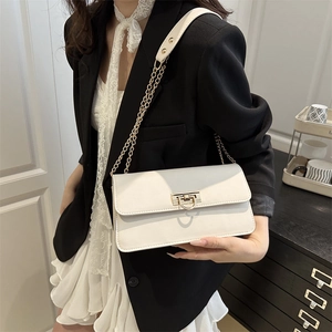 Elegante borsa a tracolla bianca con catena d'oro indossata su una modella in blazer nero