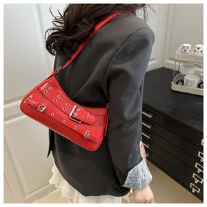 Red Y2K punk shoulder bag with metal eyelets and belt buckles on black blazer