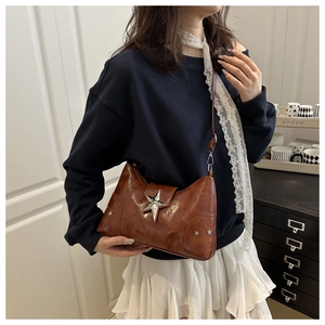 Détail du sac vintage en cuir marron avec boucle étoile argentée et clous en métal
