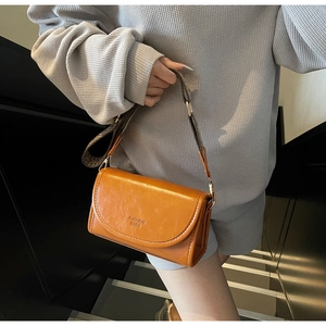 Detail of vintage small square bag in orange leather with wide geometric strap