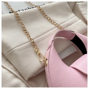 Detail of pink crescent bag side profile with light gold metal chain and leather texture