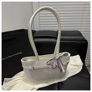 Détail d'un sac bandoulière blanc avec anneaux argentés et ruban de noeud à carreaux