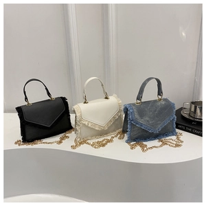 Detailed view of trendy mini square bags with fringe edges in black, white and denim