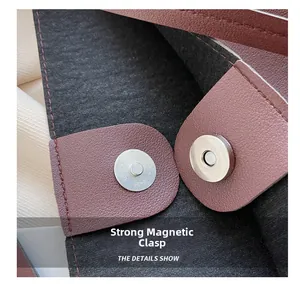 Macro detail of the silver magnetic closure on a burgundy pebbled leather tote bag