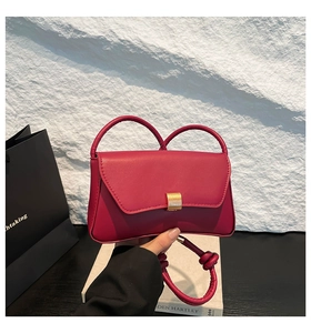 Detail of rose pink baguette bag featuring woven handle and gold rectangle clasp
