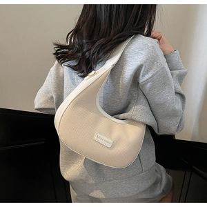Detail of woven fabric and white leather trim on a beige half-moon shoulder bag