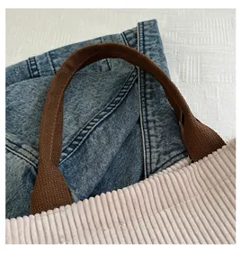 Detail of soft corduroy fabric and durable dark brown strap on a beige tote bag