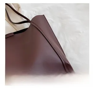 Close-up of precision stitching on dark burgundy matte leather tote bag side