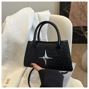 Detail of crocodile embossed black mini bag featuring a metallic silver star ornament