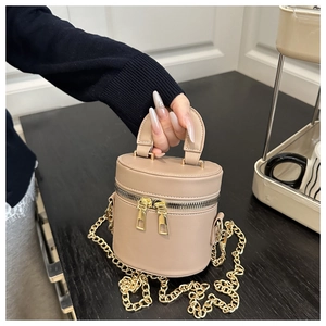 Detail der beigen Leder-Beuteltasche mit Goldreißverschlüssen und Kettentragegurt