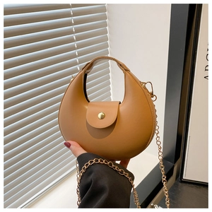 Détail du sac demi-lune caramel avec finition mate et bandoulière chaîne dorée