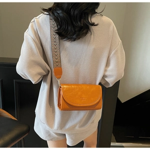 Detail of orange-brown crossbody bag with wide ethnic pattern woven shoulder strap