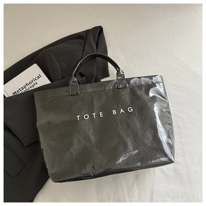 Detail of double-layer black tote bag with clear PVC finish and white TOTE BAG text