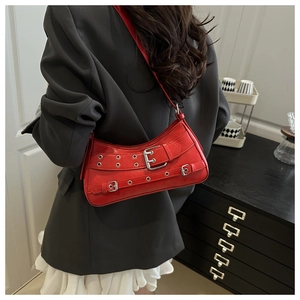 Close-up of a red leather underarm bag with silver metal buckles and eyelets detail