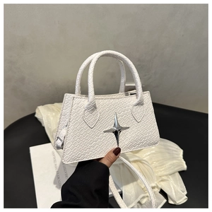 Detail of white crocodile embossed texture and silver star ornament on the crossbody bag