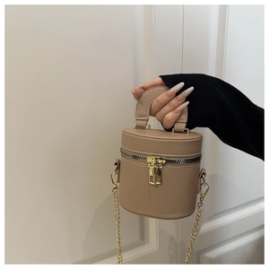 Detail einer beigen Mini-Beuteltasche aus Leder mit goldener Kette und glatter Textur