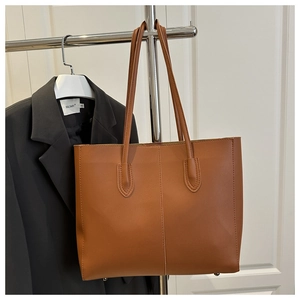 Detail of brown faux leather tote bag with vertical stitching and metal base studs