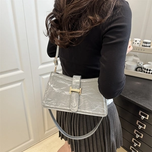 Minimalist grey baguette shoulder bag with wrinkled leather texture and golden clasp