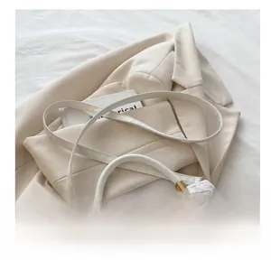 Detail of minimalist cream woven texture handbag with metallic square clasp and shoulder strap