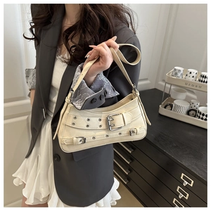 Detail showing cream underarm bag with decorative metal eyelet straps and Y2K aesthetic