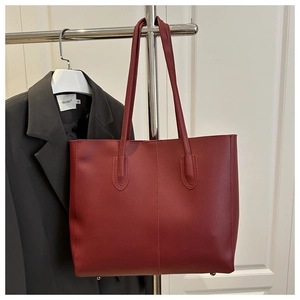 Detail of burgundy leather tote bag with metal feet studs and textured finish