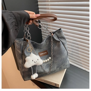 Detail of vintage grey tote bag with chain strap, pearl charm, and cloud pendant decor