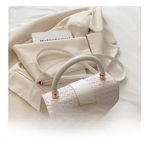 Detail of woven leather crossbody bag with round handle and gold U-shaped buckle closure