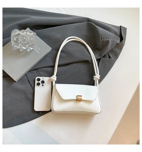 Detailed view of white leather shoulder bag with gold buckle and smartphone for scale