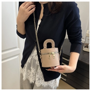 Détail du mini sac seau beige avec texture grainée et bandoulière en chaîne dorée