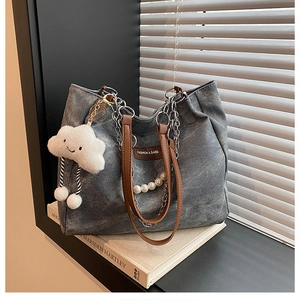 Detail of grey denim tote bag featuring leather handles and pearl chain charms